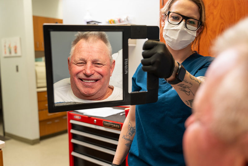 team member holding mirror fro Patient